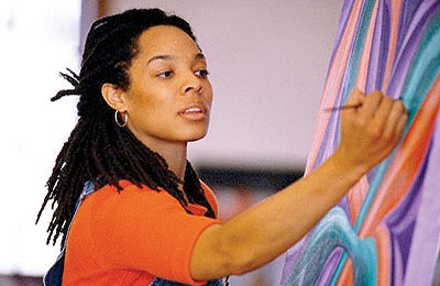 زن با پوست تیره و موهای مشکی و بلند در حال کشیدن نقاشی