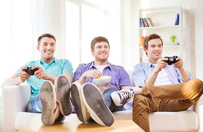 سه پسر جوان در حالی که روی کاناپه نشسته ومیخندند و دو نفر از آنها سرگرم بازیهای ویدئویی هستند و نفر وسط  کاسه‌ای در دست دارد و در حال خوردن است