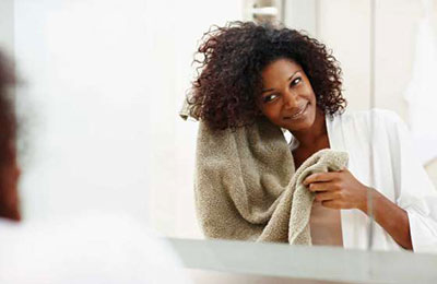 زنی سیاه پوست با موهای مجعد در حال خشک کردن موهایش با حوله