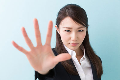 تصویر یک زن با چشمهای بادامی در حالی که دست راست خود را به علامت گفتن نه، بالا آورده
