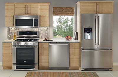 یک آشپزخانه با کابینت‌های چوبی و یخچل ساید بای ساید و ماشین ظرفشویی و گاز و فر استیل